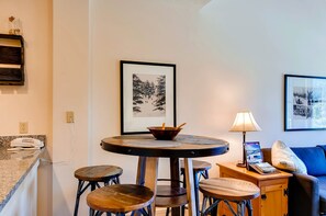 A dining area with a round table, stools, a bowl, a lamp, and a framed picture on the wall. - Silver Mill 8308 (Keystone)