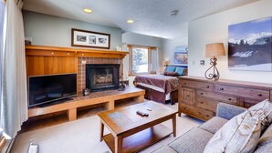 A cozy living room with a fireplace, a television, a sofa, and a coffee table. - Lenawee 1747 (Keystone)