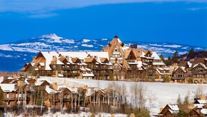 A lodge with multiple wooden buildings, a snow-covered landscape, and a mountain in the background. - Luxury renovation! Ski-in/Ski-out 5 Br Private Townhome, Top of Bachelor Gulch - majestic view & exclusive location! by RedAwning (Avon)