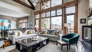 A spacious living room with large windows, a fireplace, and a cozy seating area. - Luxury renovation! Ski-in/Ski-out 5 Br Private Townhome, Top of Bachelor Gulch - majestic view & exclusive location! by RedAwning (Avon)