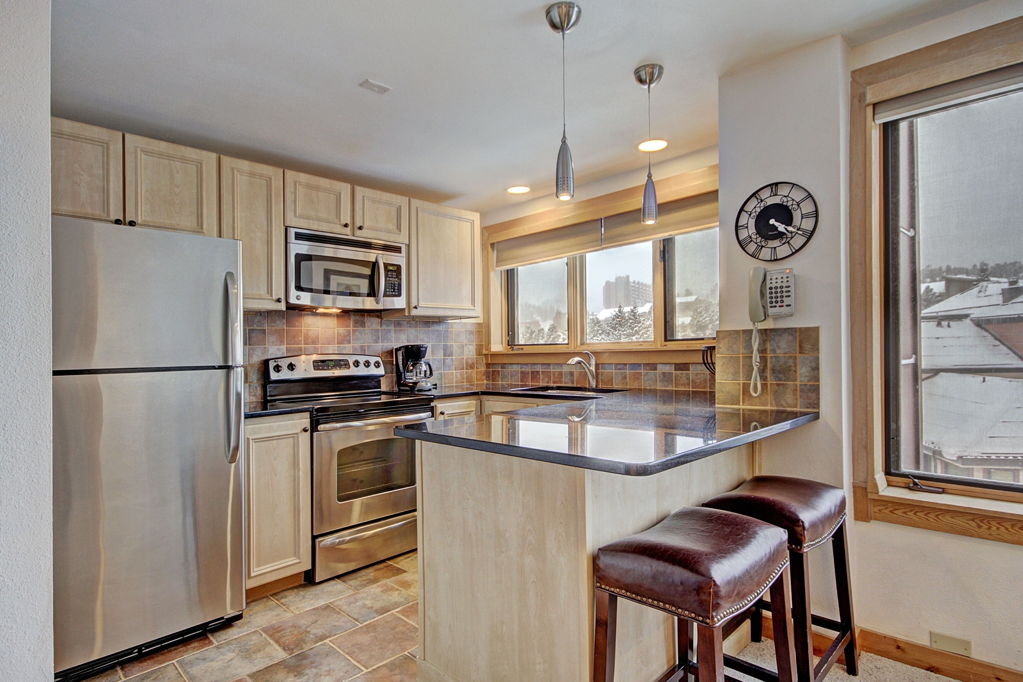 A modern kitchen with stainless steel appliances, a large island, and a view of the city through the window.