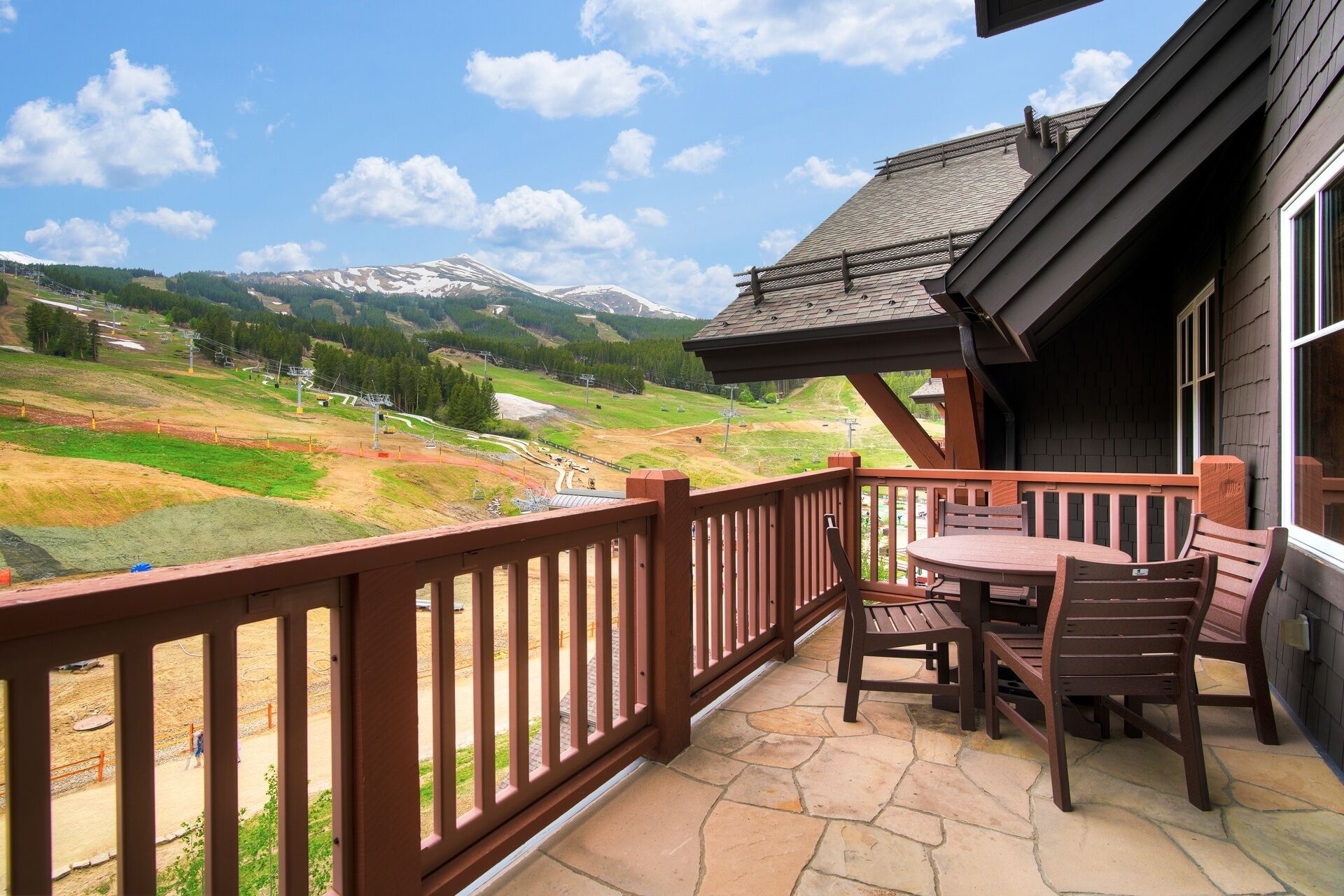 Un patio con mesa y sillas que da a un paisaje montañoso.