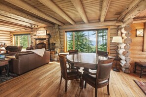 A log cabin interior with a fireplace, dining table, and seating area.