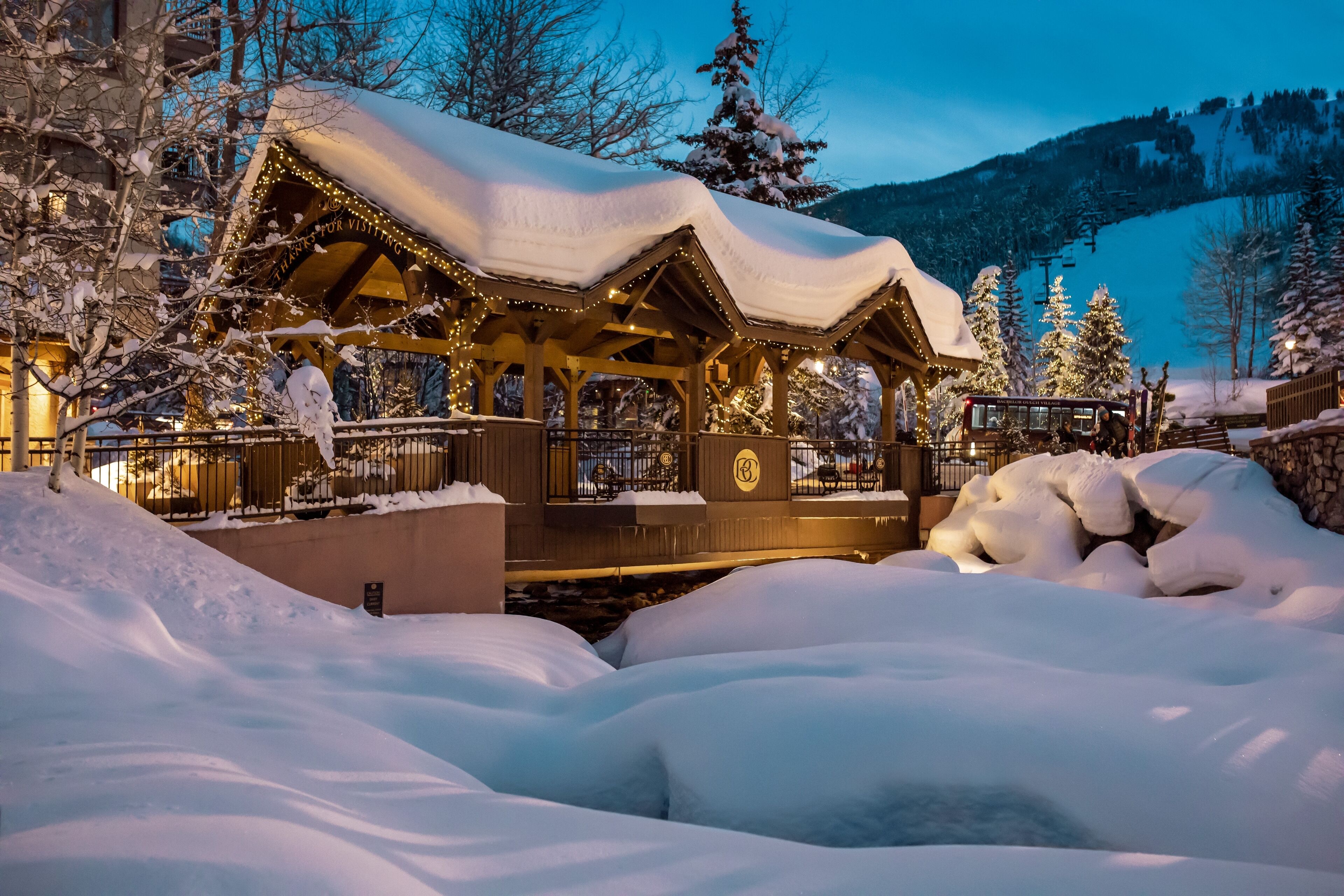 A snow-covered wooden structure with a sign reading "Transfertsur VISITING" and a logo.