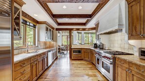 A spacious kitchen with wooden cabinets, a large stove, and ample natural light from windows. - Refined 5 BR Private Home with Private Hot Tub by RedAwning (Vail)