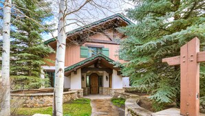 A traditional wooden house with a stone pathway leading to the entrance, surrounded by greenery and trees. - Refined 5 BR Private Home with Private Hot Tub by RedAwning (Vail)