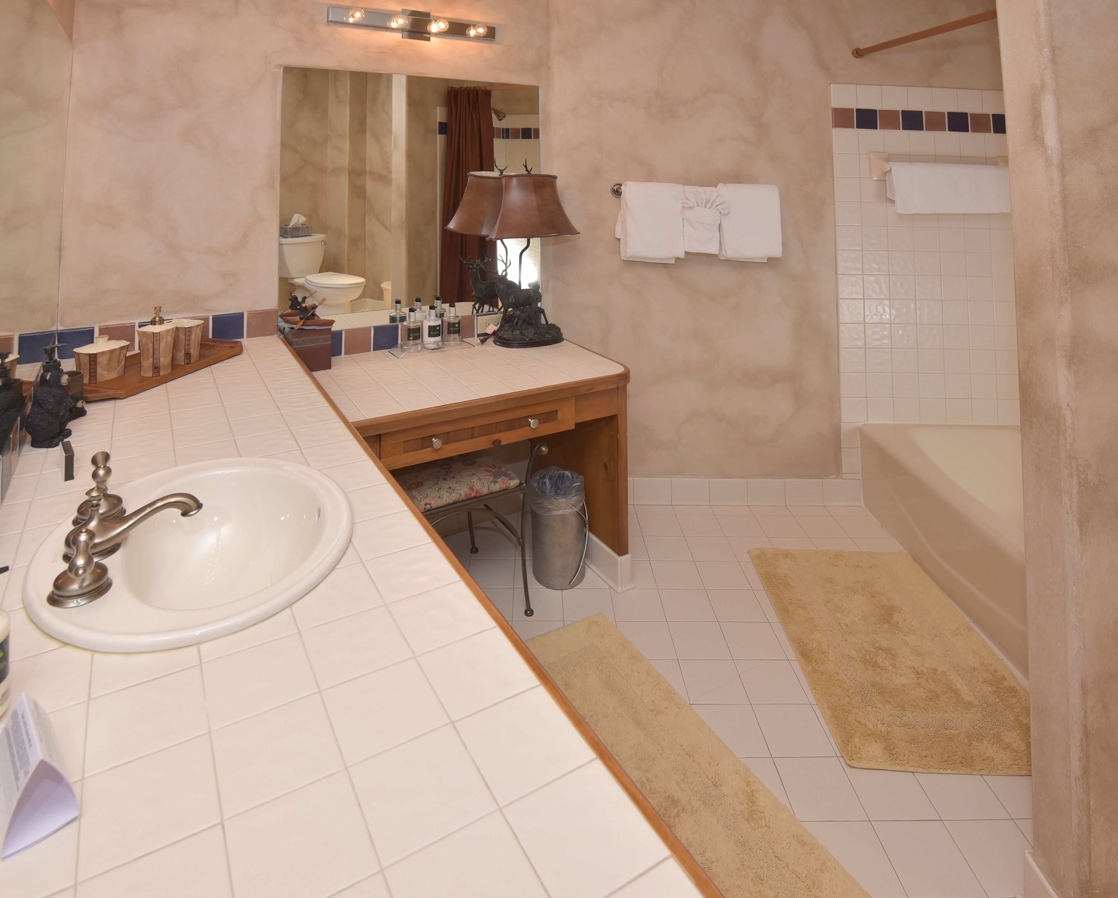 A bathroom with a sink, mirror, vanity, and a shower area.