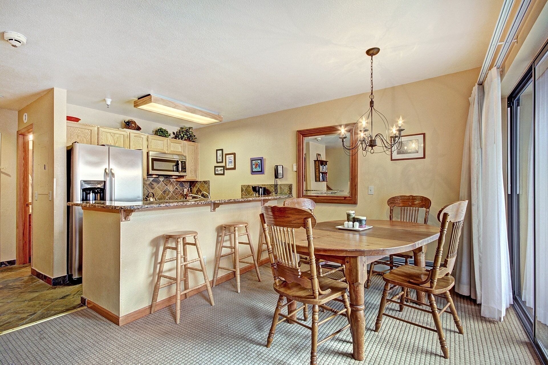 A kitchen with a central island, wooden chairs, and a chandelier.