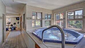 A spa area with a hot tub, exercise equipment, and large windows offering views of the outdoors.