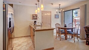 A kitchen with a central island, wooden chairs, a dining table, and a refrigerator.