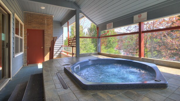 A hot tub area with a brick wall, a red door, and a window with a view of trees.