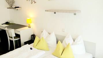 Habitación de hotel con cama, escritorio, silla, lámpara y un adorno en la pared.