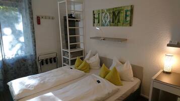A bedroom with a bed, pillows, a ladder, a shelf, and a lamp.