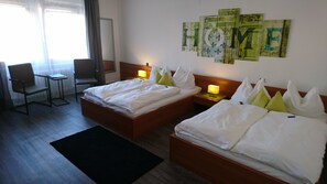 Une chambre d’hôtel avec deux lits, une chaise, une table de chevet et un mur décoré d’œuvres d’art.
