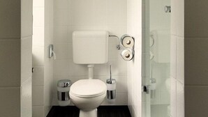 Ein modernes Badezimmer mit Toilette in Weiß, einer Duschkabine aus Glas und einem dunklen Holzboden.