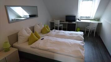 Habitación de hotel con dos camas, un escritorio con ordenador y una silla.