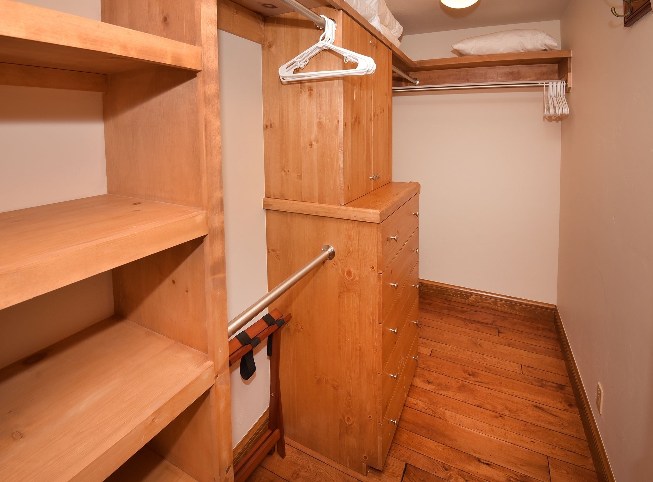 Un placard en bois avec des étagères, une tringle pour suspendre les vêtements et une commode intégrée.