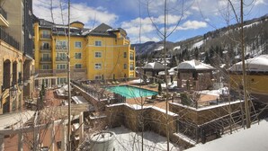 A hotel with a pool area, surrounded by snow-covered mountains and a clear sky.
