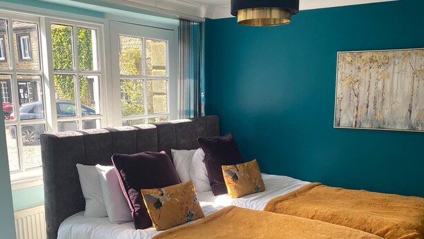 Una camera da letto con un letto grande, un comodino, una finestra con tende e un quadro appeso al muro.