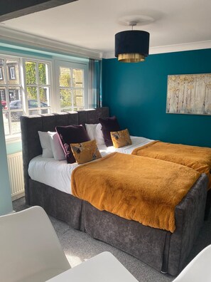 A bedroom with a large bed, a bedside table, a window with curtains, and a painting on the wall. - The Ancient Unicorn (Barnard Castle)