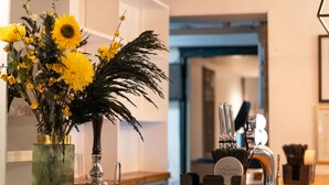 Un tavolo in legno con un vaso di fiori gialli, un oggetto decorativo e un portapenne con strumenti di scrittura.