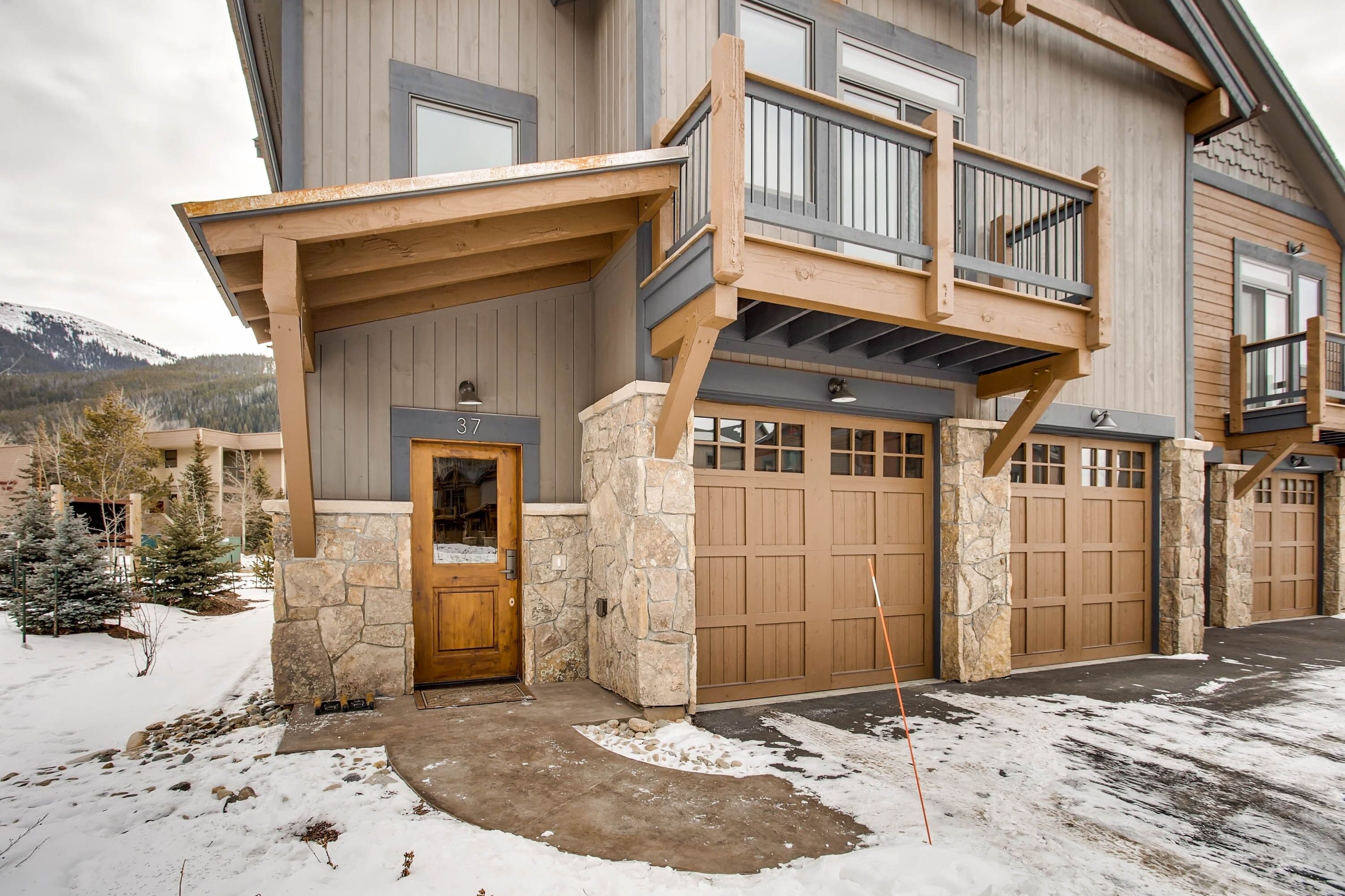 A two-story house with a stone entrance, a balcony, and a garage.