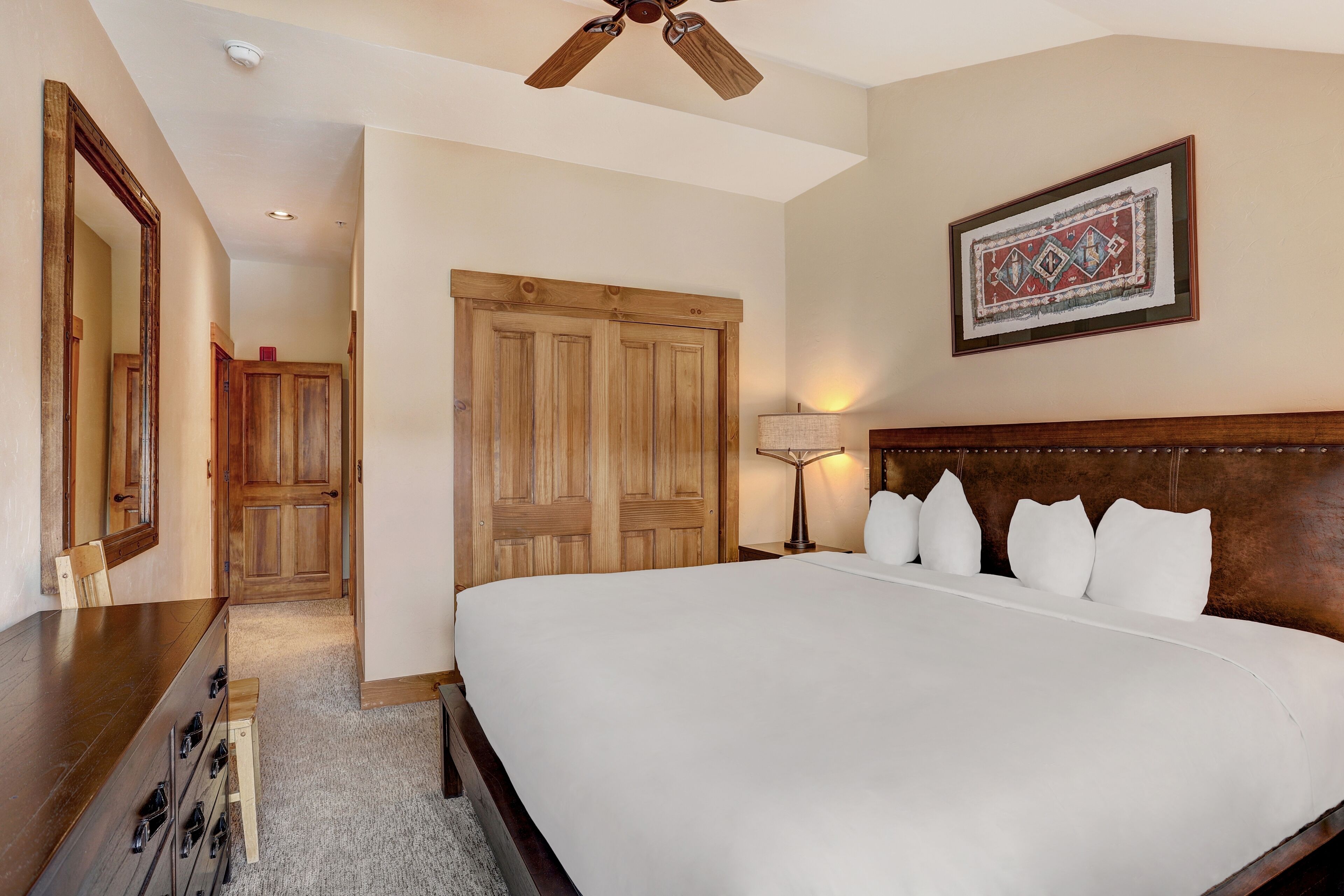 Un dormitorio con una cama grande, un armario de madera y un ventilador de techo.