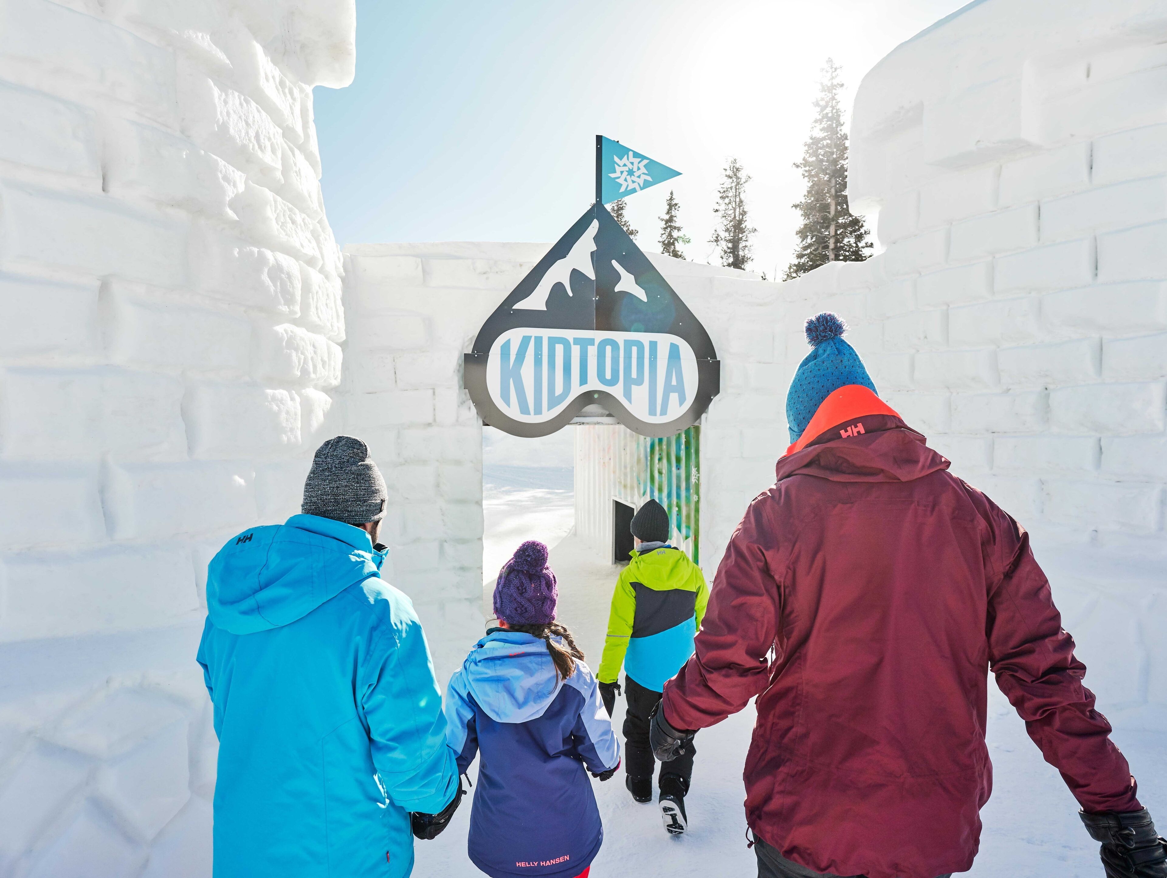 A group of people walking through a snow-covered area with a sign that reads "KIDTOPIA".