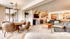 Un salón amplio con comedor, chimenea y cocina al fondo.