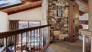 A spacious room with a stone wall, wooden ceiling beams, a view of a swimming pool, and a cozy seating area with a view. - 2 BR Condo at The Lodge at Vail View of Gore Range by RedAwning - Save 20% on 7+ Nights! (Vail)