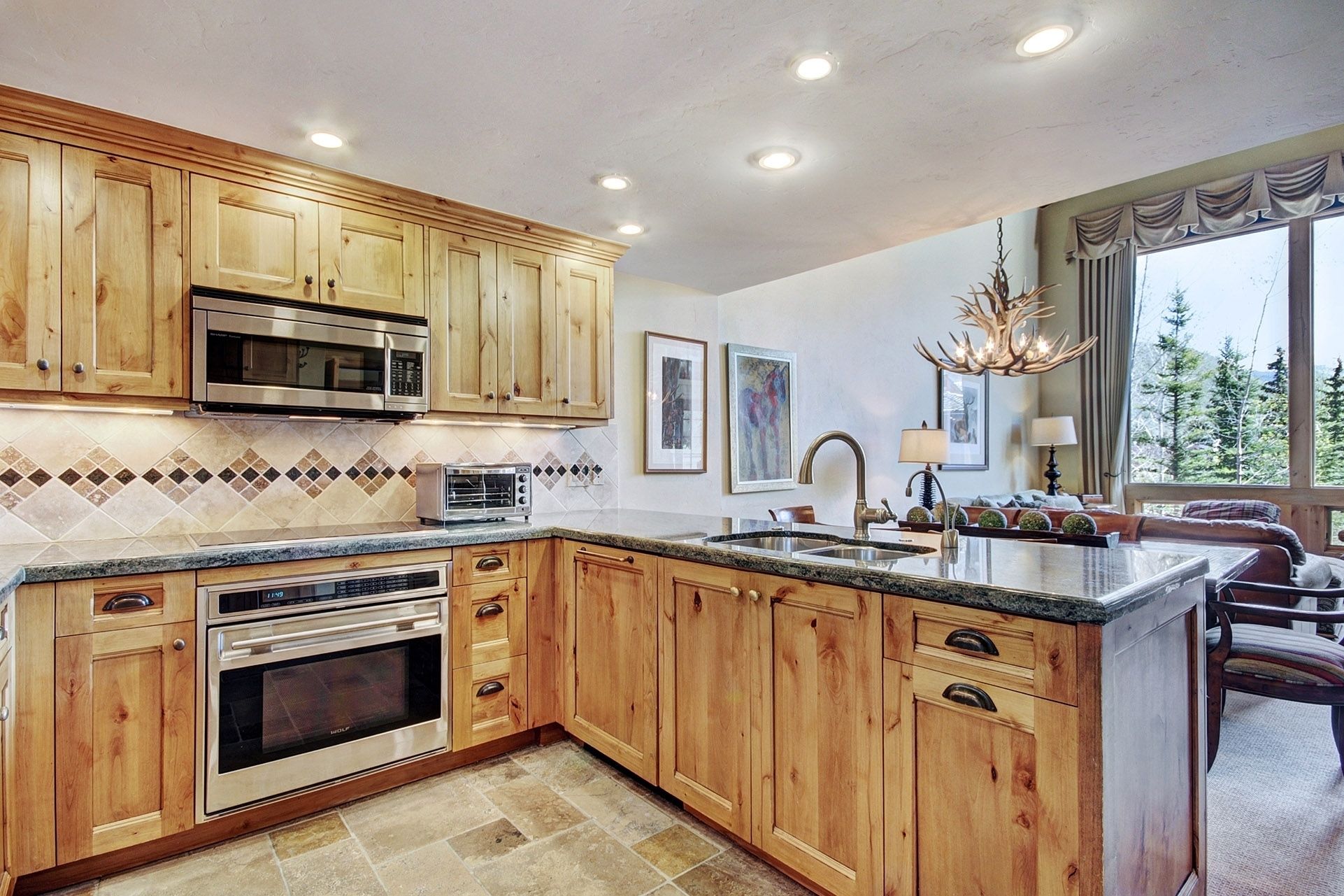 A kitchen with wooden cabinets, a microwave, a toaster, a sink, and a chandelier.