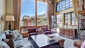 Un salon spacieux avec de grandes fenêtres, une cheminée et une vue sur la montagne.