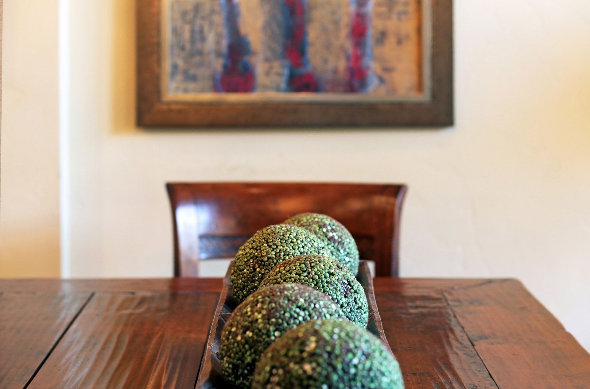 A wooden table with a row of green, textured objects.