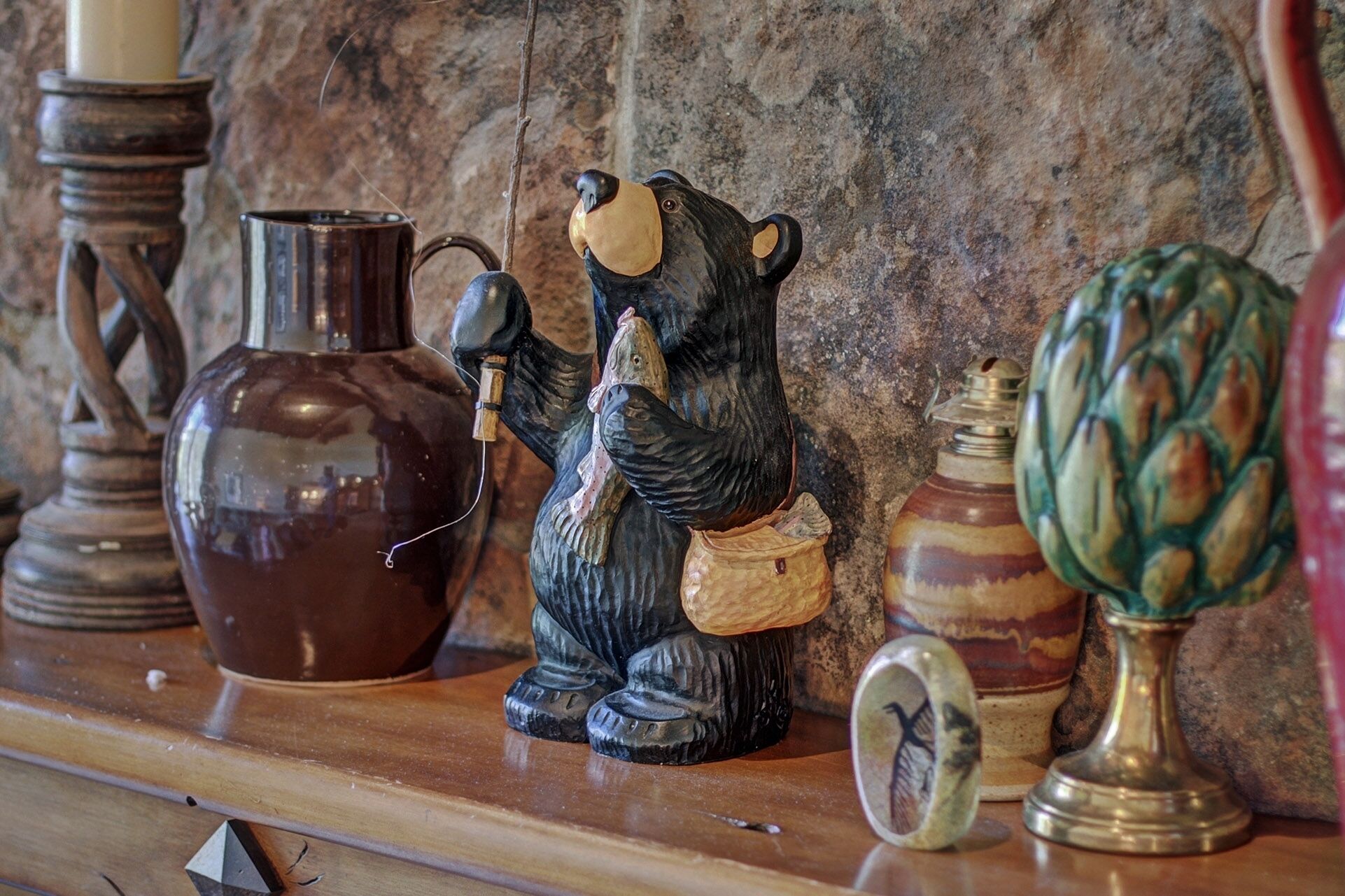 A shelf with various decorative items including a ceramic bear figurine, a vase, and a candle holder.