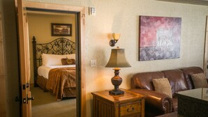 A hotel room with a bed, a nightstand with a lamp, a leather sofa, and a painting on the wall.