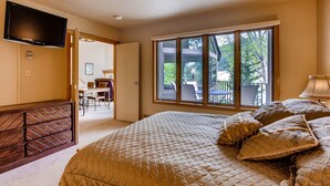 Ein Schlafzimmer mit einem großen Bett, einem an der Wand montierten Fernseher und einem Fenster mit Blick ins Freie.