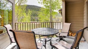 Ein Balkon mit Tisch und Stühlen, der auf eine bewaldete Landschaft blickt.