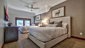 A bedroom with two beds, a ceiling fan, and artwork on the walls.