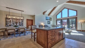 A spacious kitchen with a large island, wooden cabinetry, and a dining area with a table and chairs.