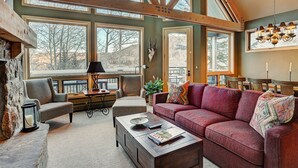 A spacious living room with large windows, a fireplace, and a cozy seating area. - Slopeside Living - 3br 4ba At Pines Lodge 3 Bedroom Condo by RedAwning (Avon)