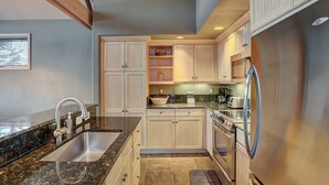 A kitchen with granite countertops, stainless steel appliances, and wooden cabinets. - Slopeside Living - 3br 4ba At Pines Lodge 3 Bedroom Condo by RedAwning (Avon)