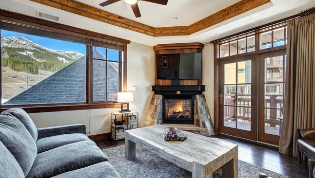 A cozy living room with a fireplace, large windows, and a view of mountains. - Luxury  At Base Of Peak 8, Steps From Winter Activities 2 Bedroom Condo by RedAwning (Breckenridge)