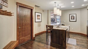A modern kitchen with a wooden door, a bar area, and a large island. - Luxury  At Base Of Peak 8, Steps From Winter Activities 2 Bedroom Condo by RedAwning (Breckenridge)