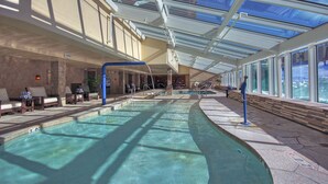 A large indoor swimming pool with clear glass ceilings, sunlit areas, and seating along the sides. - Luxury  At Base Of Peak 8, Steps From Winter Activities 2 Bedroom Condo by RedAwning (Breckenridge)