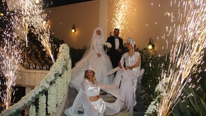 Ceremonia de boda con invitados en escalones, rodeada de arreglos florales blancos e iluminación decorativa.