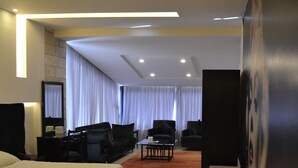 Habitación de hotel con una cama grande, dos sillones, una mesita de centro y un televisor.