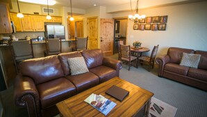 A living room with two brown leather sofas, a wooden coffee table, and a dining area with a wooden table and chairs. - Stay in Comfort while Enjoying Valley Views by RedAwning (Park City)