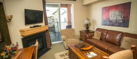 A living room with a fireplace, a television, a sofa, a coffee table, and a painting on the wall.
