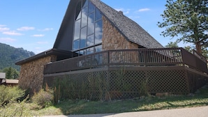 A modern building with a stone facade and large windows, featuring a balcony and a view of the surrounding landscape. - Sky View In The Rockies -- Ev #3473 3 Bedroom Home by RedAwning (Estes Park)