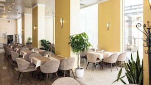 A restaurant with multiple tables and chairs, potted plants, and a bright interior. - Rome Palace Deluxe (Sunny Beach)